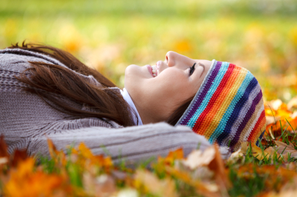 Young woman laying on dry leaves and enjoying life